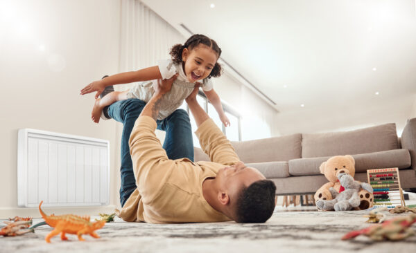 pere avec sa fille jouant au salon radiateur electrique a inertie Aterno en arrière plan