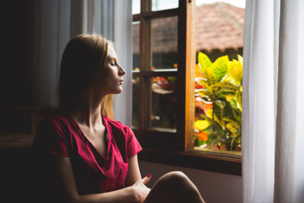 femme devant assise devant une fenêtre ouverte
